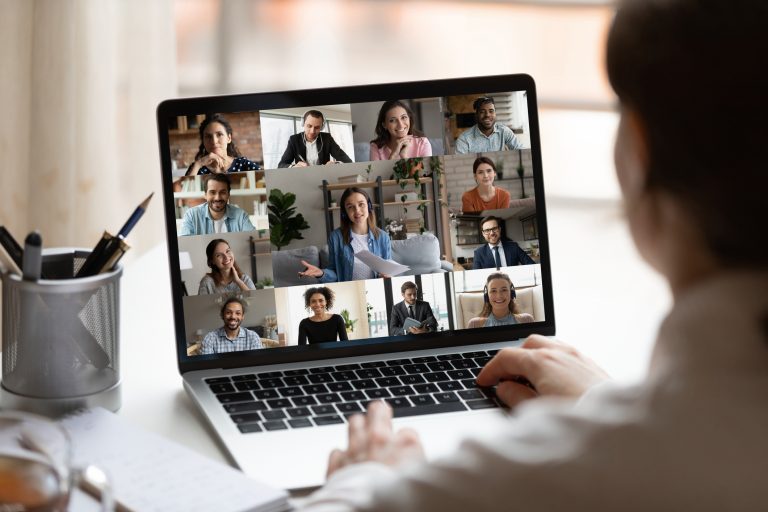 Rear close up view of female employee brainstorm talk on video call with diverse colleague on laptop. Woman speak engaged in team group discussion, have webcam company online meeting or briefing.