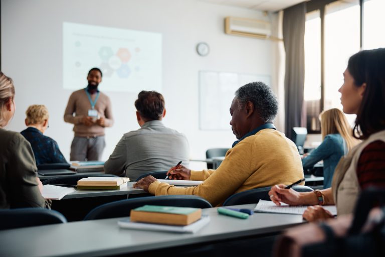 African American senior man taking notes during education training class.