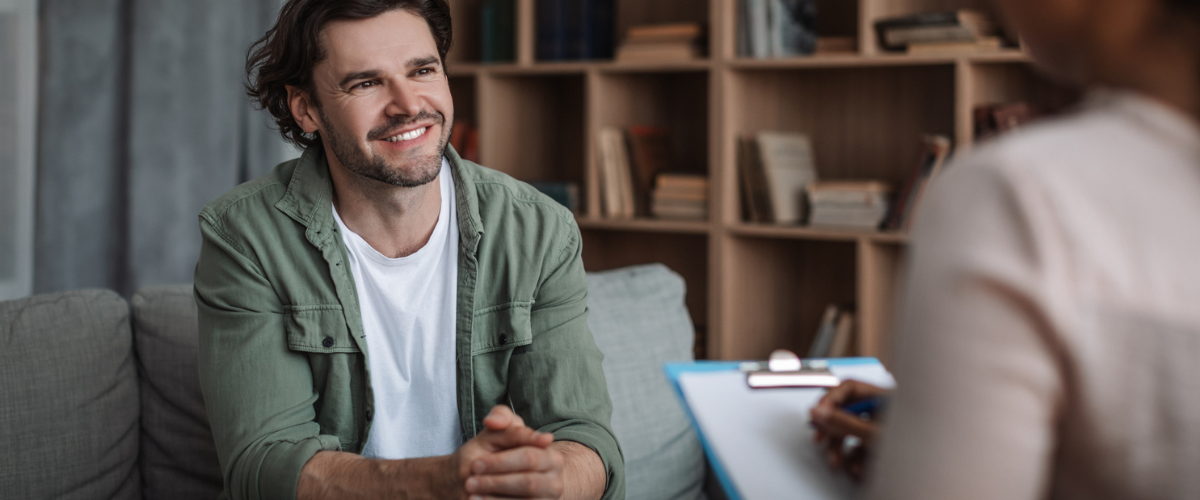 Millennial black woman psychologist consults smiling european guy in modern clinic interior