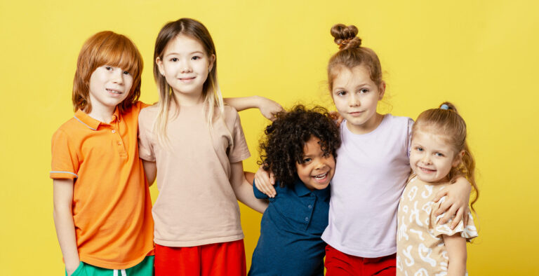 Five diverse children smiling and hugging, celebrating childhood friendship and unity