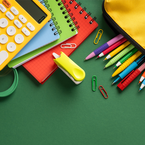 Assortment of school supplies on green background, calculator, pens and pencils, notebooks, etc.