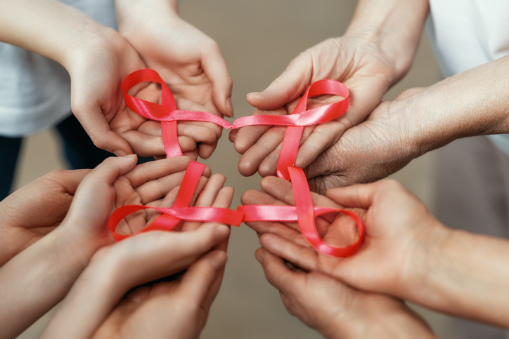 Hands with red satin ribbons symbolizing concept of red ribbon week