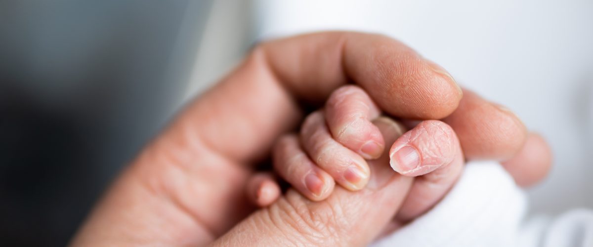 hand of newborn baby who has just been born holding the finger of his father's hand.