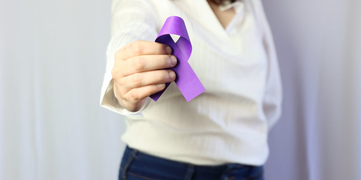 Woman wearing casual clothes holding in the hands a purple ribbon representing overdose prevention