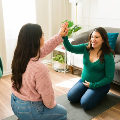 Happy midwife and pregnant woman sharing a joyful high five during a supportive home visit, celebrating connection and trust in motherhood Happy doula and pregnant woman sharing a joyful high five during a supportive home visit, celebrating connection and trust in motherhood
