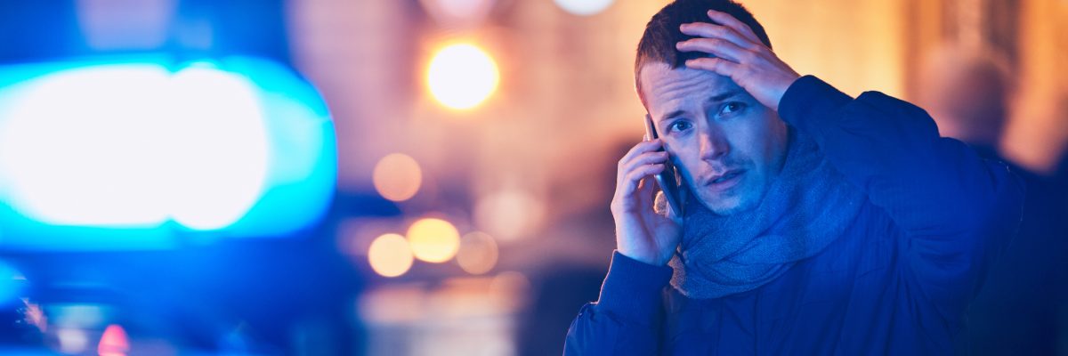 Young man calling after a crisis situation on city street. Themes crime, emergency medical service, fear or help.