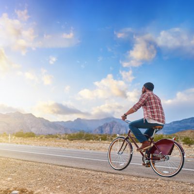 man riding bike into nevada sunset on empty highway man riding bike into nevada sunset on empty highway by himself
