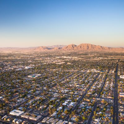 Aerial view across urban suburban communities seen from Las Vegas Nevada with streets, mountains, rooftops, and homes